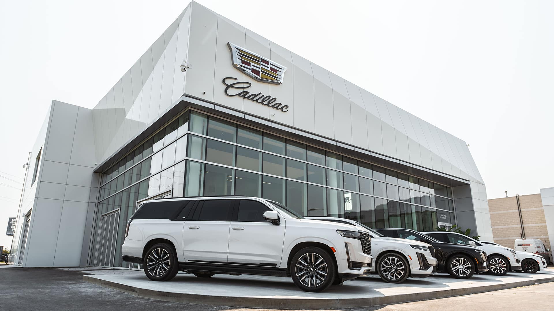 Cadillac dealership exterior with multiple luxury SUVs parked in front.