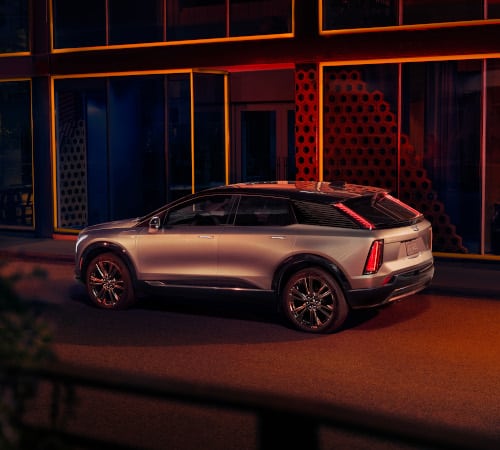 Silver SUV parked in front of a modern building with vibrant lighting at night.