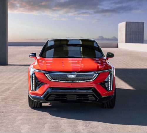 Red Cadillac SUV parked on a modern concrete surface with a cloudy sky backdrop.