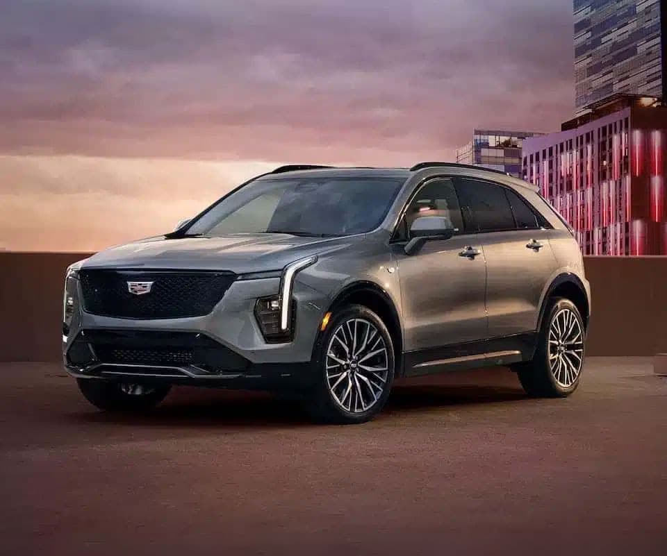 Silver SUV parked on an urban rooftop at sunset with modern buildings in the background.